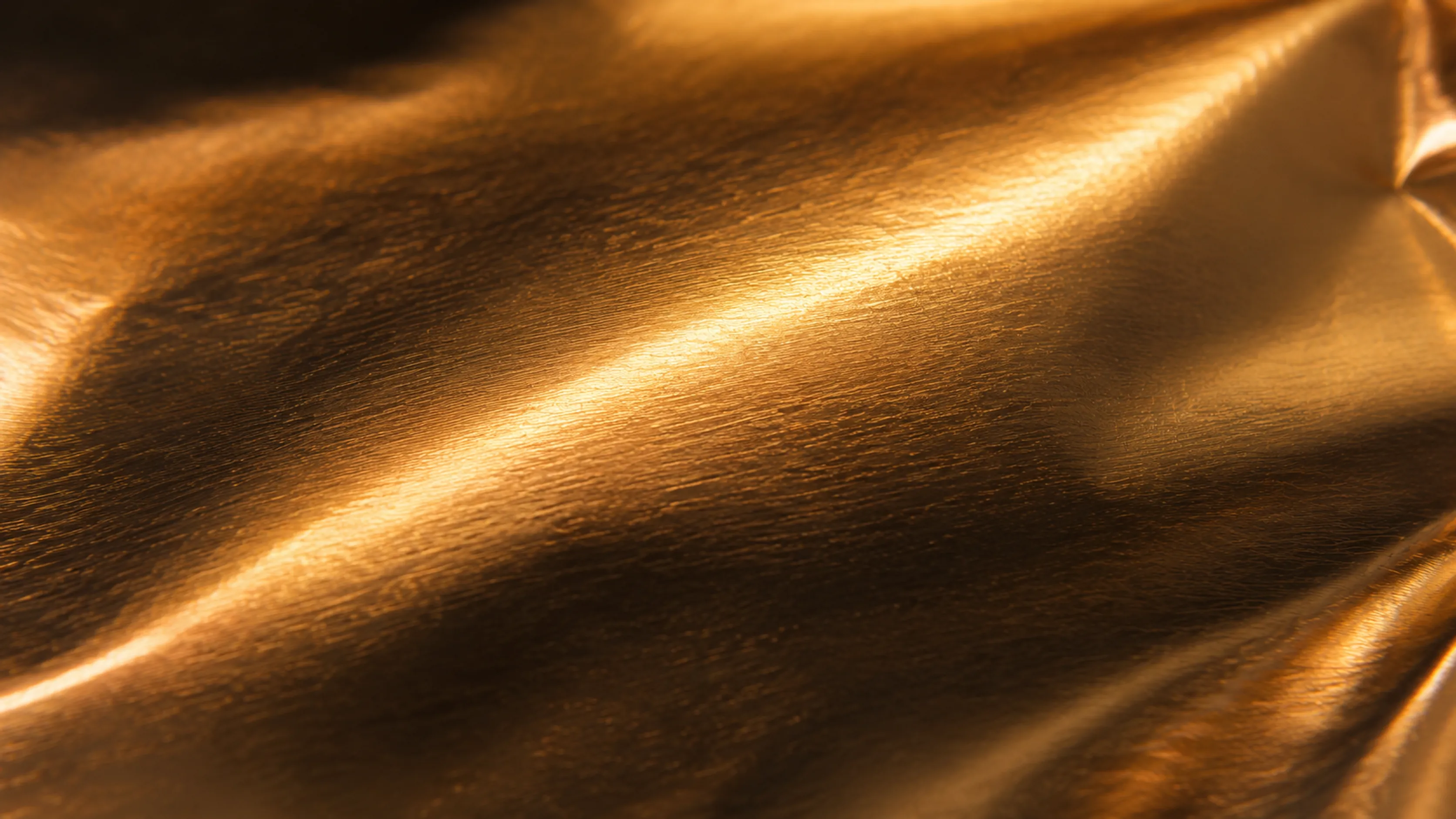 Brushed metallic foil pouch material macro with warm light streak — Sparal Packaging finish option